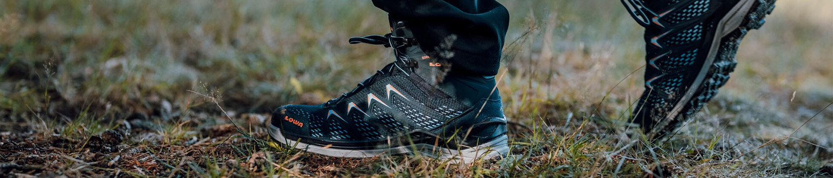 Twee halfhoge wandelschoenen van Lowa in het gras.