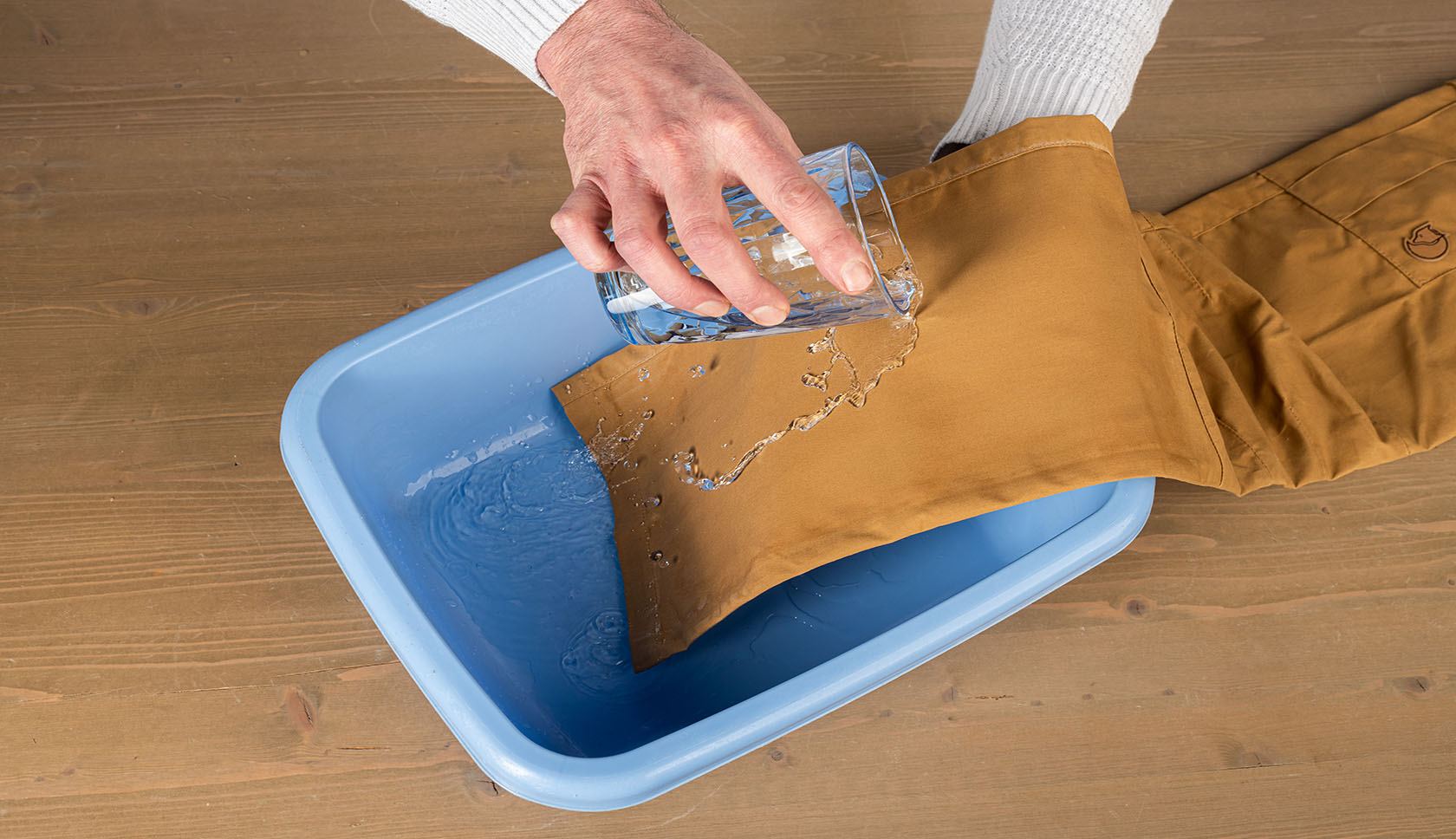 hand leegt een glaasje water over de fjallraven broek